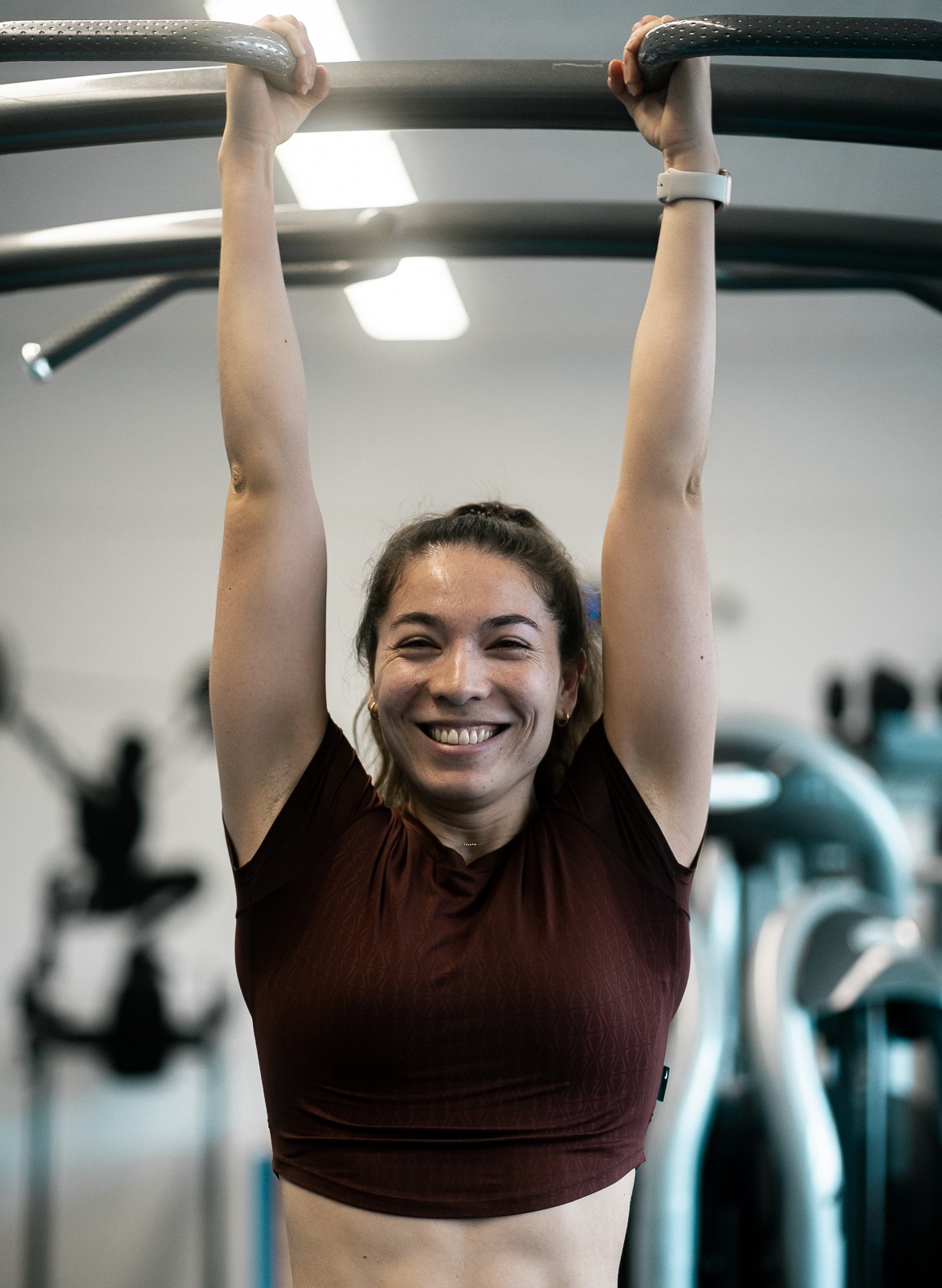 Personal Trainerin Ellise Meyer hängt an Rack und lächelt in die Kamera