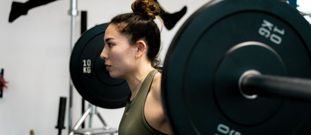 Personal Trainerin Ellise Meyer mit Langhantel auf dem Rücken